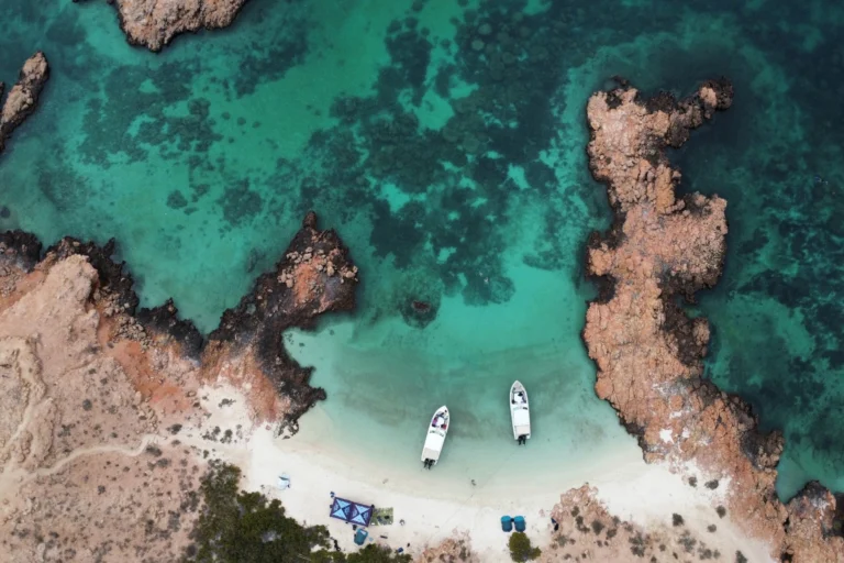 Two boats anchored off an island beach at the Daymaniyat Islands, seen from above