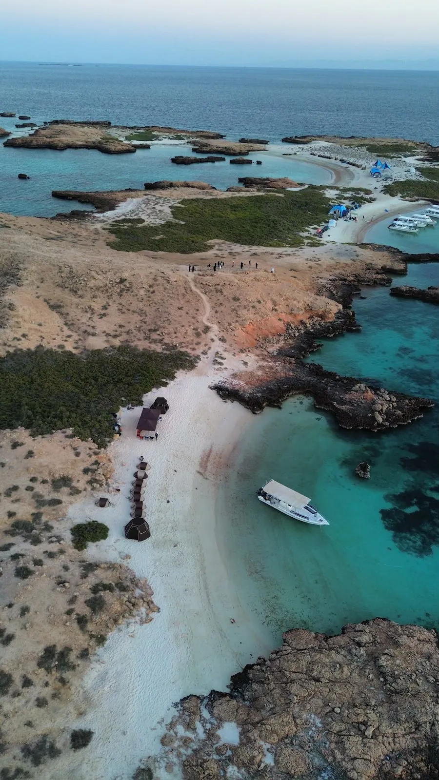 Aerial view of a boat off a long white beach with the other Daymaniyat Islands on the horizon
