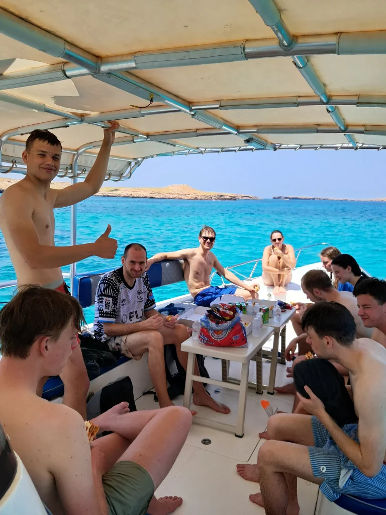 Large group of guests laughing and giving a thumbs-up on the boat deck during a Daymaniyat Islands trip